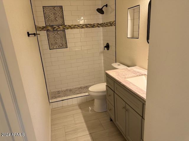 bathroom featuring vanity, toilet, and a tile shower