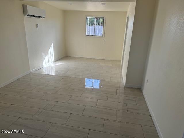 unfurnished room featuring an AC wall unit