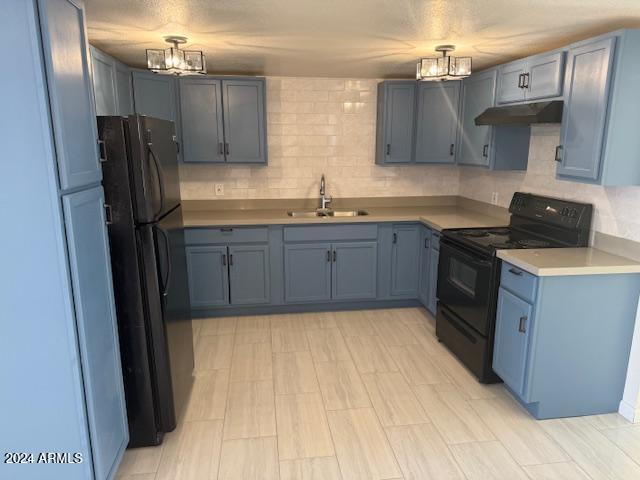 kitchen with black appliances, backsplash, sink, and blue cabinetry