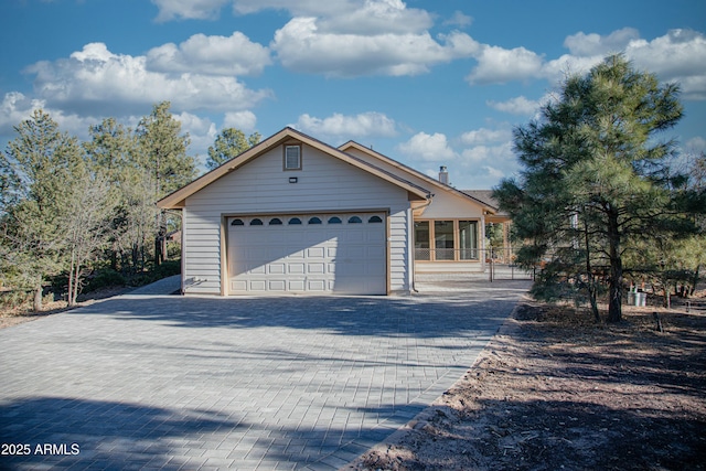 view of front of house with decorative driveway, an attached garage, and a chimney