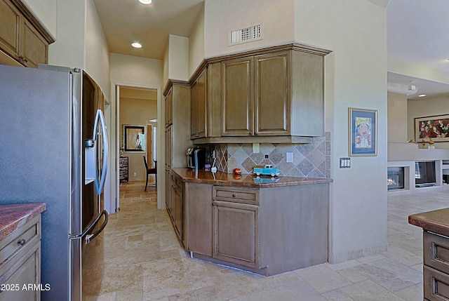 32516 N 68th Pl, Scottsdale, AZ 85266 - kitchen with stainless steel refrigerator with ice dispenser, stone tile floors, backsplash, recessed lighting, and a glass covered fireplace