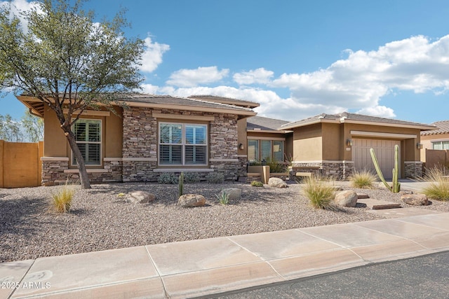 prairie-style house with a garage, stone siding, fence, and stucco siding