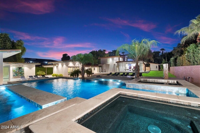 pool at dusk with a patio and an in ground hot tub