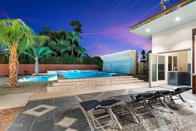 pool at dusk featuring a patio