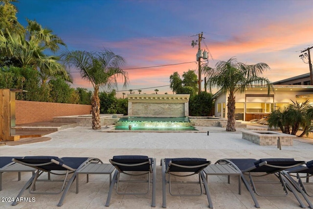 pool at dusk featuring a patio