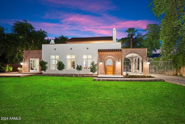 view of front of home with french doors and a yard