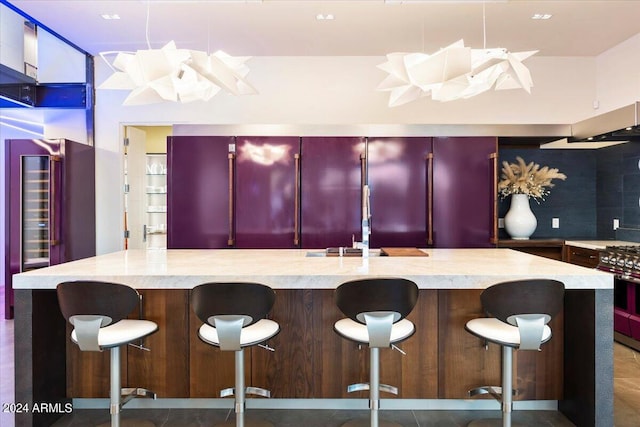 kitchen with hanging light fixtures, stainless steel range with gas stovetop, a spacious island, a breakfast bar area, and decorative backsplash