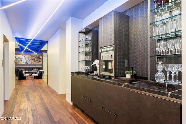 bar featuring dark brown cabinetry, dark hardwood / wood-style flooring, and sink