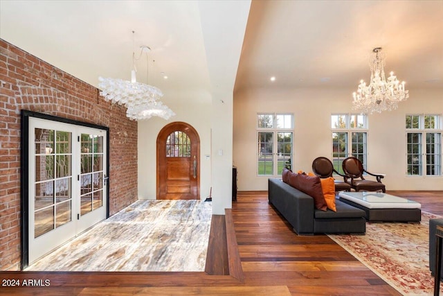 foyer featuring an inviting chandelier, brick wall, and dark hardwood / wood-style flooring