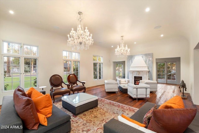 living room with a notable chandelier, a wealth of natural light, a high end fireplace, and hardwood / wood-style floors