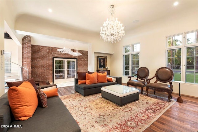 living room with brick wall, hardwood / wood-style flooring, a chandelier, and a healthy amount of sunlight