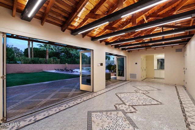 doorway with vaulted ceiling with beams, wooden ceiling, and carpet floors