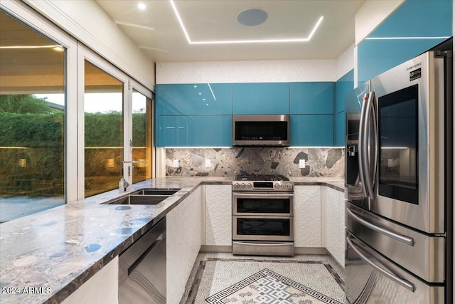 kitchen with light stone counters, tasteful backsplash, blue cabinetry, stainless steel appliances, and sink