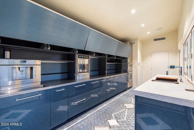 kitchen featuring sink, blue cabinetry, stainless steel counters, carpet floors, and vaulted ceiling