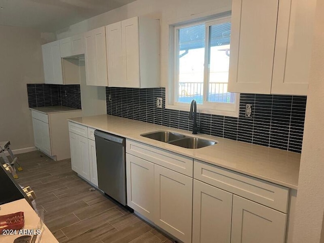 kitchen with white cabinets, hardwood / wood-style flooring, stainless steel dishwasher, and sink