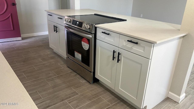 kitchen with electric stove and white cabinetry