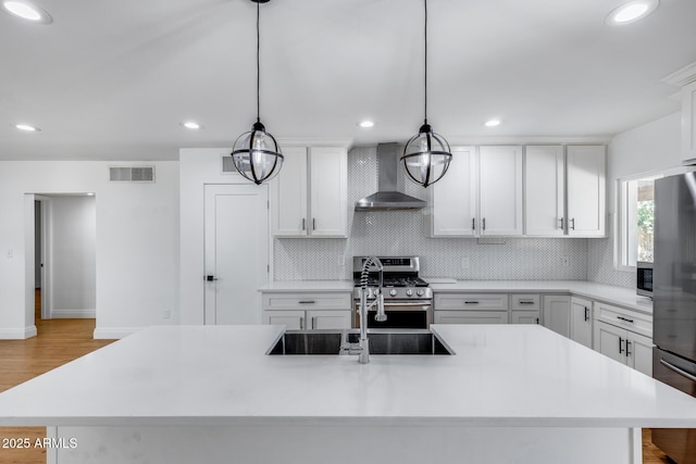 2336 E Flower St, Phoenix, AZ 85016 - kitchen with wall chimney exhaust hood, appliances with stainless steel finishes, decorative backsplash, light countertops, and a kitchen island with sink