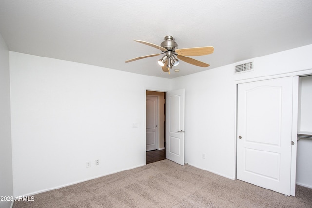 unfurnished bedroom with ceiling fan, a closet, and light carpet