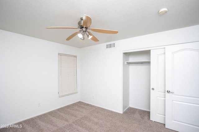 unfurnished bedroom featuring ceiling fan, a closet, and light carpet