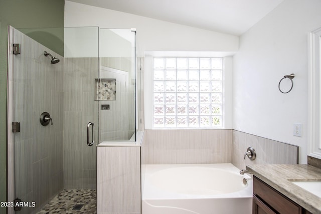 bathroom featuring plus walk in shower, vaulted ceiling, and vanity