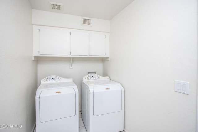 laundry area with washing machine and clothes dryer and cabinets