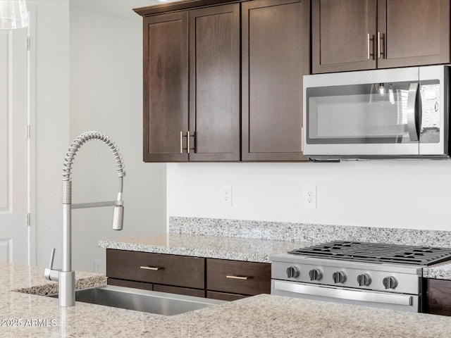 kitchen featuring gas range, stainless steel microwave, dark brown cabinets, and a sink