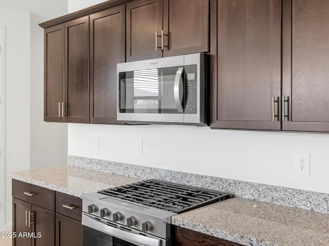 kitchen featuring dark brown cabinetry, appliances with stainless steel finishes, and light stone counters