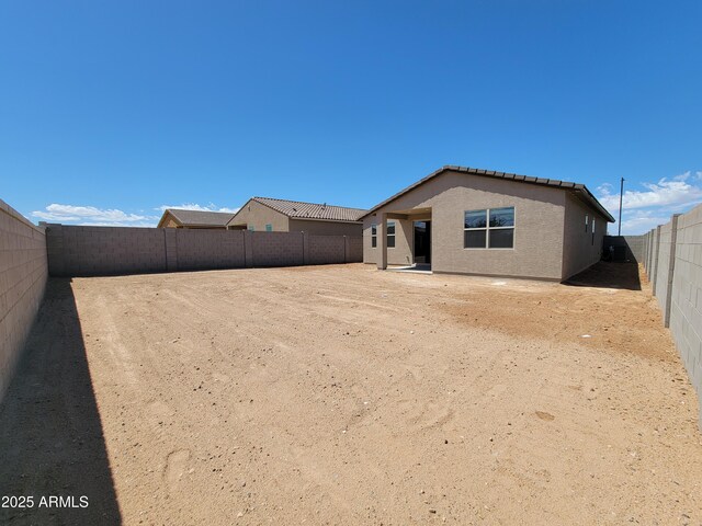 back of house with a fenced backyard and stucco siding