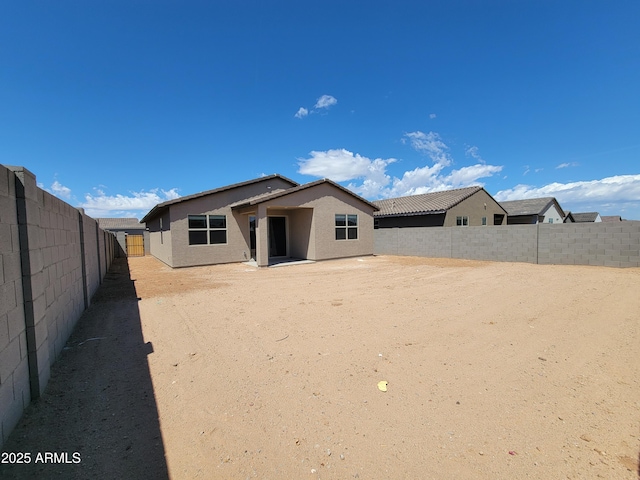 rear view of house with a fenced backyard and stucco siding