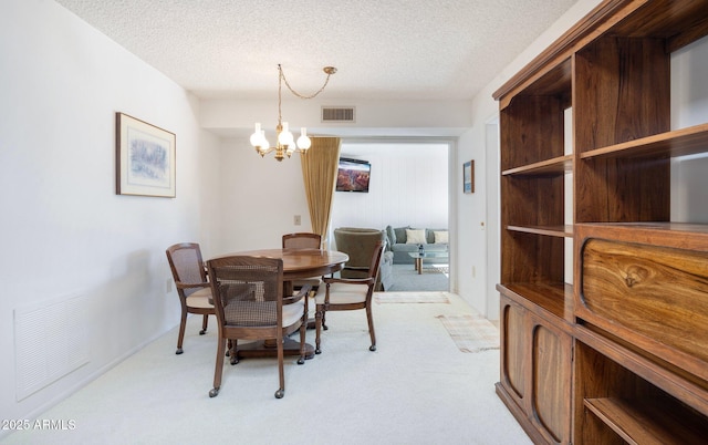 carpeted dining space featuring a notable chandelier and a textured ceiling