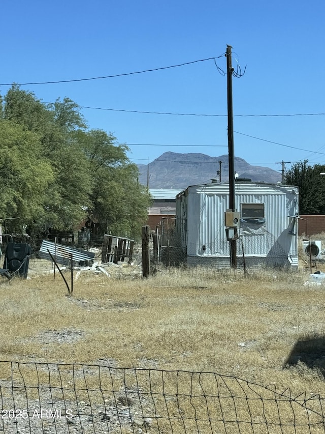 view of yard featuring a shed, fence, a mountain view, and an outdoor structure
