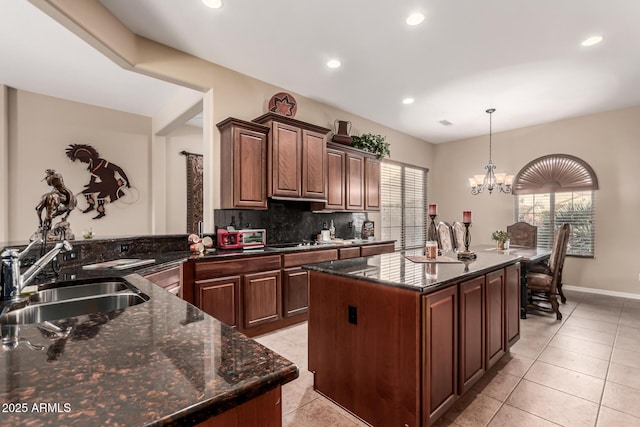 kitchen featuring a notable chandelier, sink, a kitchen island, kitchen peninsula, and pendant lighting