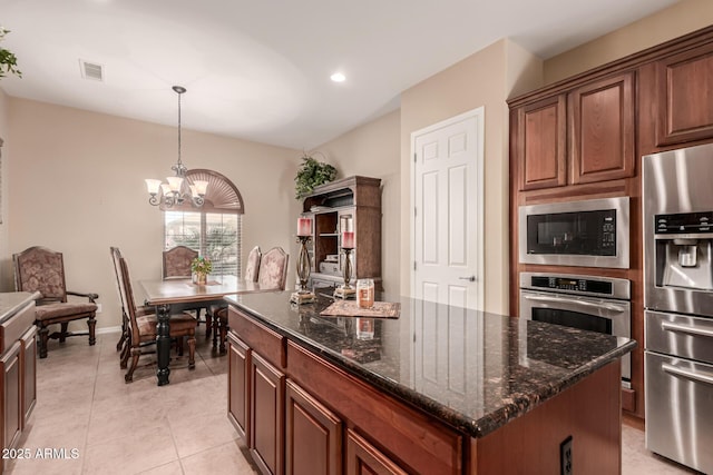 kitchen featuring appliances with stainless steel finishes, a center island, dark stone counters, hanging light fixtures, and a chandelier