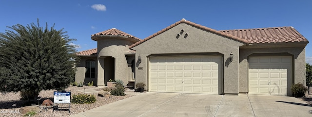 mediterranean / spanish-style home featuring a tiled roof, a garage, concrete driveway, and stucco siding