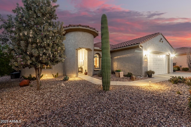 mediterranean / spanish-style home featuring stucco siding, driveway, an attached garage, and a tile roof