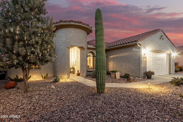 mediterranean / spanish-style home with stucco siding, driveway, an attached garage, and a tile roof