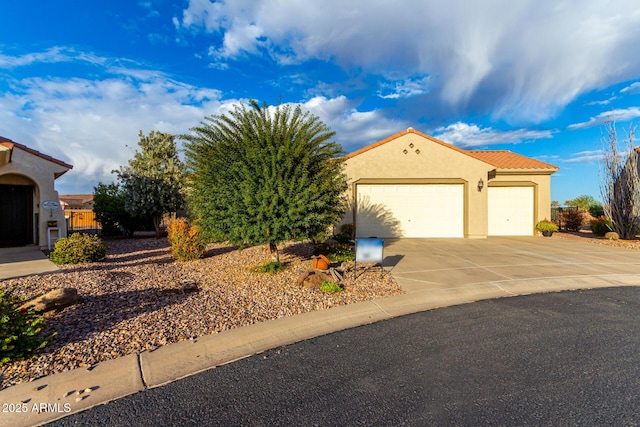 mediterranean / spanish home featuring concrete driveway, a tiled roof, a garage, and stucco siding