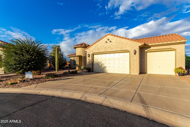 mediterranean / spanish-style home featuring concrete driveway, a tiled roof, a garage, and stucco siding