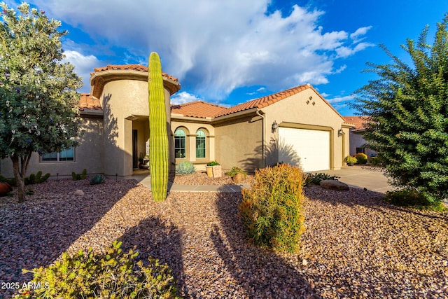 mediterranean / spanish house with stucco siding, driveway, an attached garage, and a tile roof