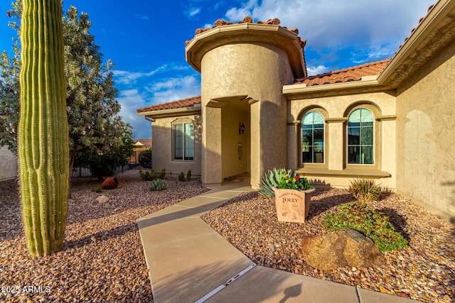 doorway to property featuring stucco siding and a tile roof