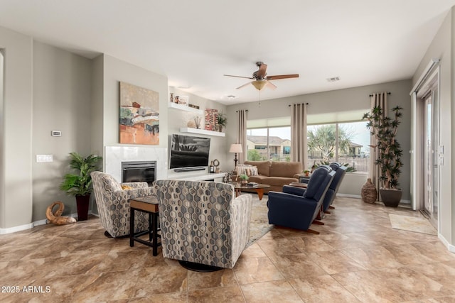 living room featuring a premium fireplace, baseboards, visible vents, and ceiling fan