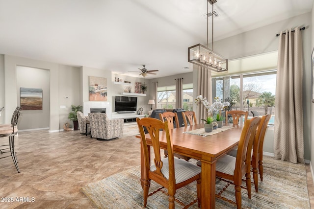 dining space featuring visible vents, ceiling fan with notable chandelier, a tile fireplace, and baseboards