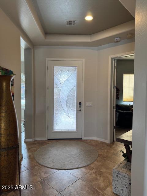 entryway featuring a tray ceiling, baseboards, and visible vents