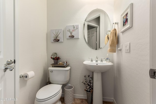 half bathroom featuring toilet, baseboards, and a sink