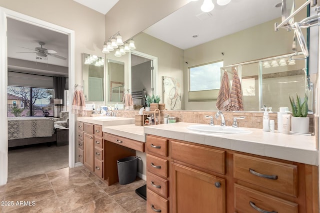 bathroom featuring tiled shower, double vanity, ceiling fan, a sink, and connected bathroom