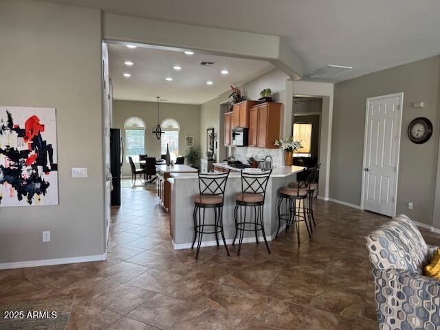 kitchen with a kitchen bar, baseboards, brown cabinets, and backsplash