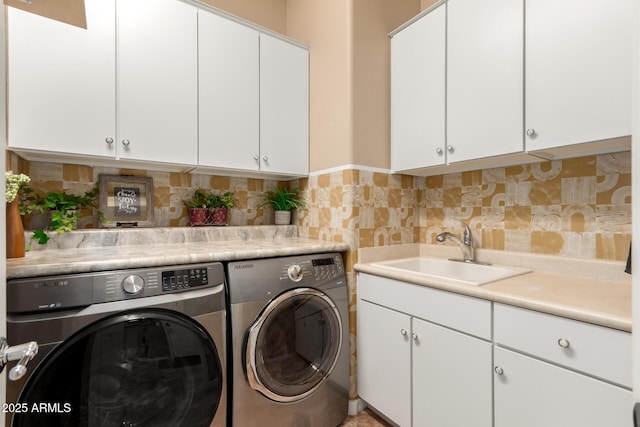 washroom with washing machine and clothes dryer, cabinet space, and a sink