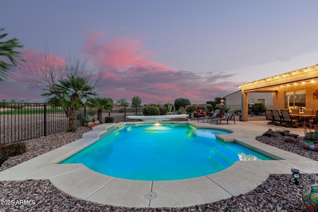 pool at dusk featuring a patio, fence, and a fenced in pool