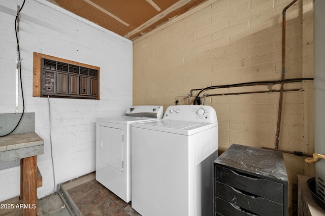 laundry area with independent washer and dryer and brick wall