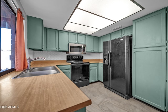 kitchen with backsplash, sink, black appliances, and green cabinetry